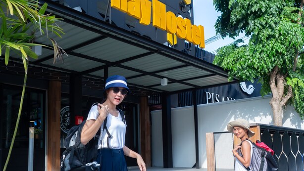 A person descending stairs outside a building with a sign that reads "Ray Hotel". - Ray Hostel (Chiang Mai)