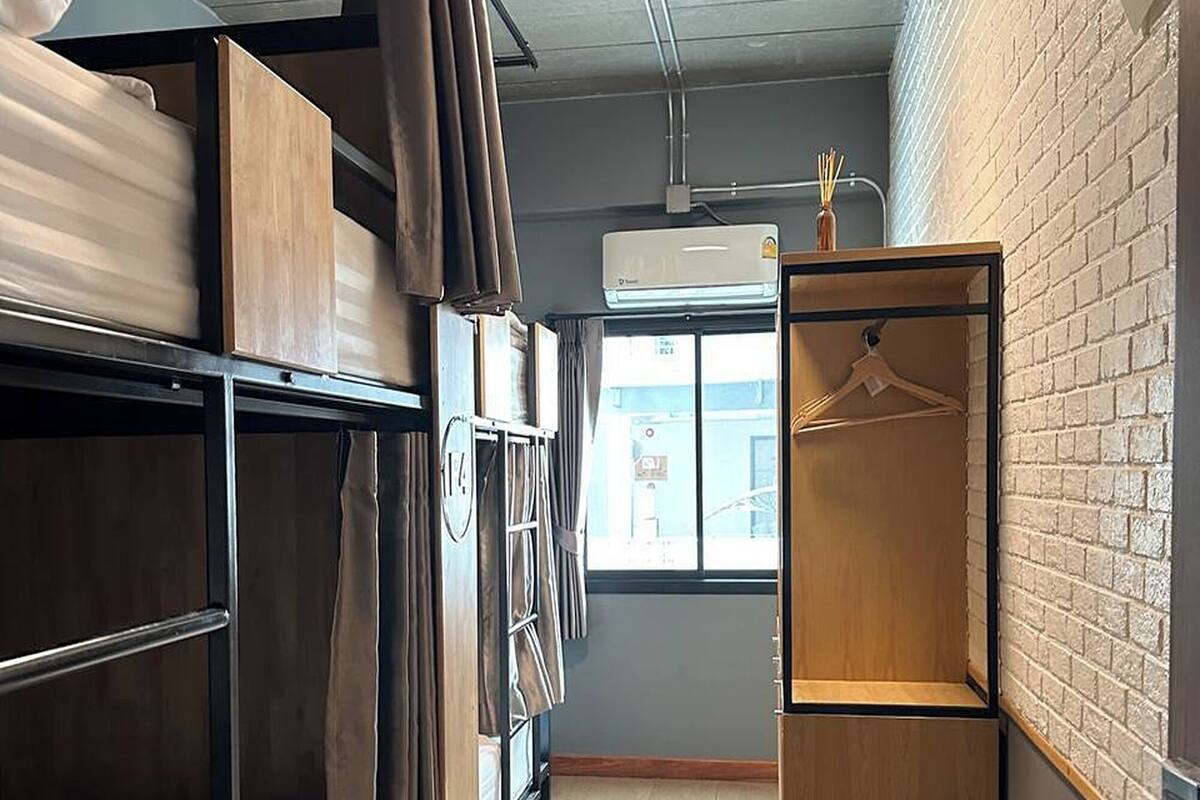 A dormitory room with bunk beds, a wardrobe, and a heater.