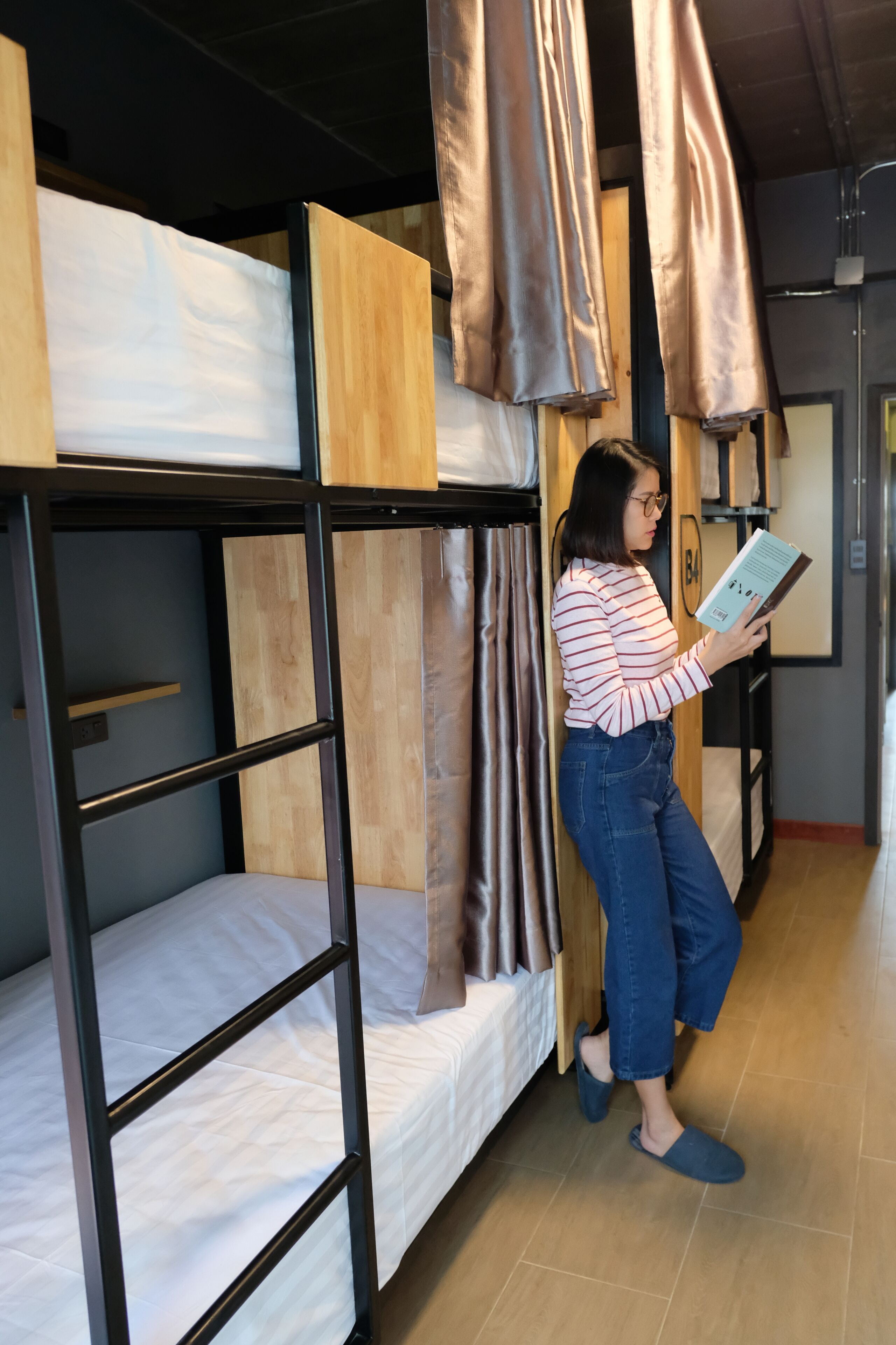 Habitación con literas y una persona leyendo un libro.
