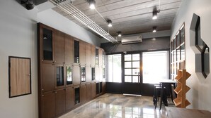A spacious room with a polished marble floor, wooden lockers, and a large window providing natural light. - Ray Hostel (Chiang Mai)