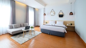 A modern hotel room with a bed, sofa, and a small table with a laptop. - Lopi Hotel (Makassar)