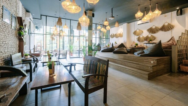 A modern cafe with wooden furniture, woven light fixtures, and a brick wall. - Lopi Hotel (Makassar)