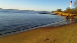A sandy beach with calm water, a pier extending into the water, and a lighthouse in the background. - Best of Kollmar, app. with terrace for 2 pers. absolutely quiet - Best of Kollmar, (Kollmar)