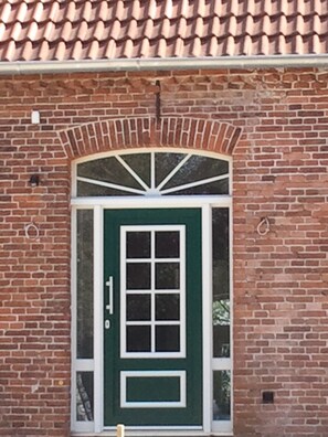 Traditional brick building with a charming entrance featuring a green door and decorative arch.