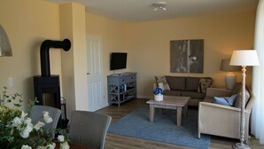 A living room with a fireplace, sofa, coffee table, and a television.