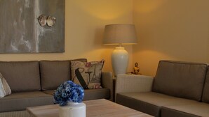 A living room with a sofa, a coffee table with a vase of flowers, a lamp, and a Buddha statue.