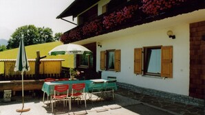 An outdoor seating area with a table and chairs, a table umbrella, and a flower-adorned balcony.