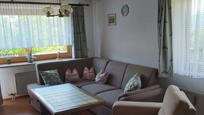 A cozy living room with a sofa, a small table, and a window with curtains.