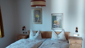 A bedroom with a wooden bed, two nightstands, a ceiling fan, and two wall-mounted lamps.