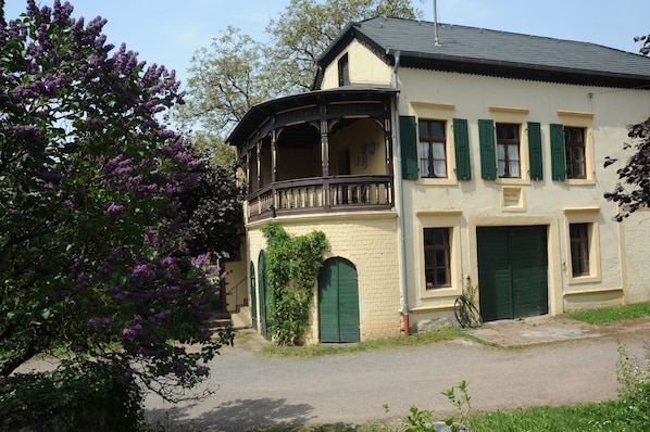 A two-story building with a balcony, green shutters, and a sign that reads "Hotel".