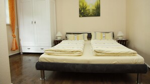 A double bed with two nightstands, a white wardrobe, and a painting on the wall.