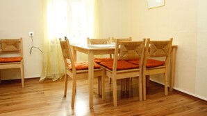 A dining area with a wooden table and chairs, a bench, and a window with curtains.