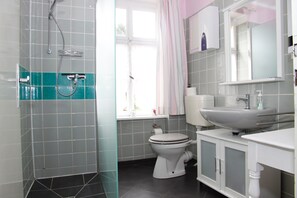 A modern bathroom with a shower, toilet, and sink.