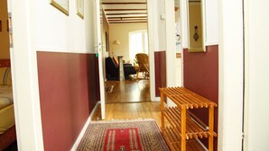 A hallway with a wooden bench, a patterned rug, and a door leading to another room.