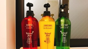 Three bottles of natural herb shampoo, conditioner, and body soap on a shelf. - GH One More Heart Enmachi 3 (Kyoto)