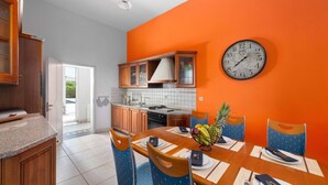 A kitchen with wooden cabinets, a dining table set for four, and a clock on the wall. - The idyllic oasis of well-being (Soroni)