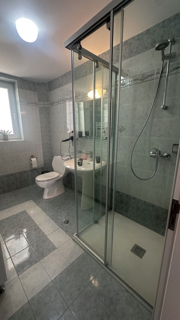 A modern bathroom with a glass-enclosed shower, a toilet, and a sink.