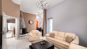 A modern living room with a beige sofa, a black coffee table, and a fireplace. - The idyllic oasis of well-being (Soroni)