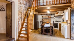 Eine rustikale Küche mit einer Holztreppe, einem Esstisch mit Stühlen und einer Kücheninsel.