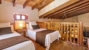 Ein gemütliches Schlafzimmer mit zwei Betten, Holzbalken, einem kleinen Fenster und einer Holzwand mit Haken.