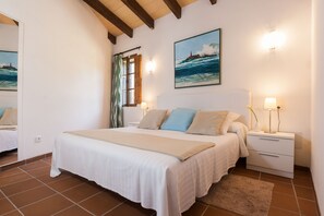 Een slaapkamer met een bed, nachtkastjes, een spiegel en een schilderij van een zeegezicht.