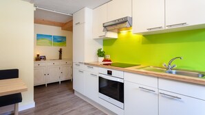 Una cocina moderna con armarios blancos, salpicadero verde, horno empotrado y un lavamanos.