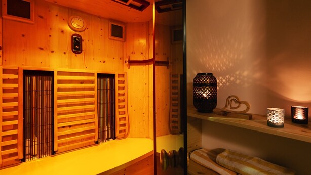Un cuarto de spa de madera con un banco, un reloj y repisas con velas.