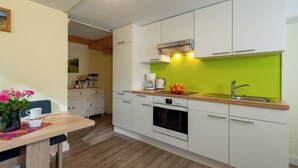 Una cocina moderna con armarios blancos, salpicadero verde y encimera de madera.