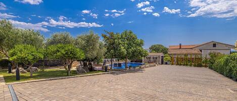 Un patio con piscina, edificios de piedra y árboles.