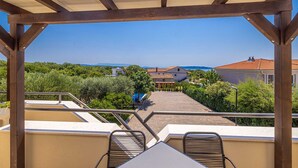 A covered outdoor area with a view of a residential neighborhood, a pool, and a clear sky.