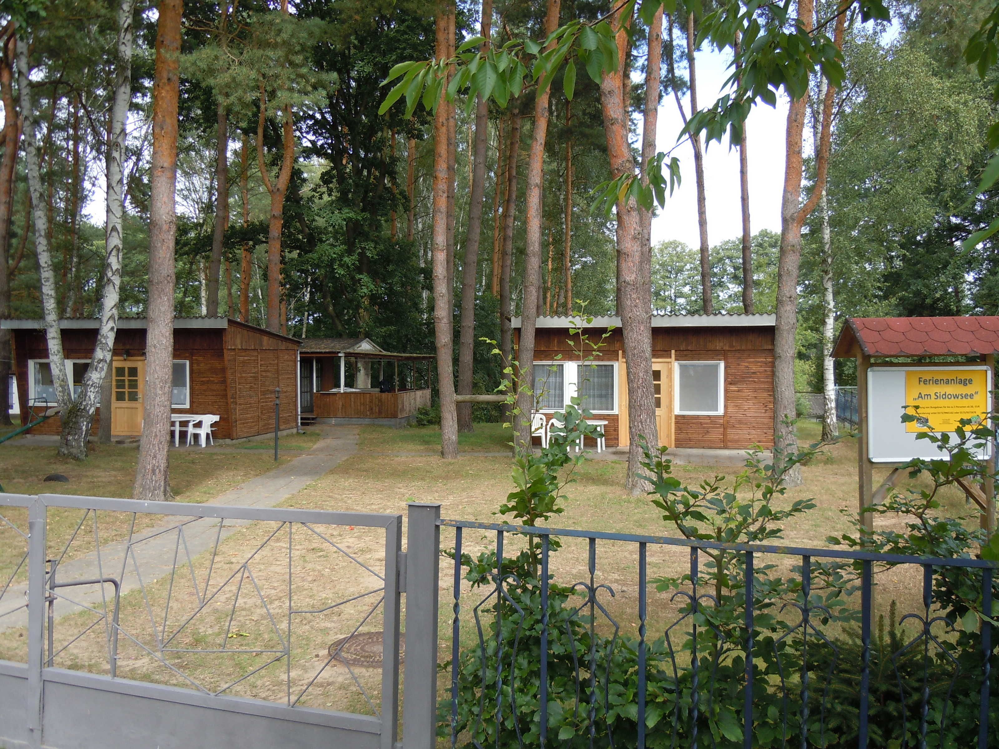 Skovområde med hytter og en indhegnet indgang.