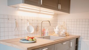 A kitchen with a wooden countertop, a sink, and cabinets. There is a bowl of fruit on the counter. - Gemütl cottage + wifi, 1.5 km to the beach, fenced playground / lawn (Pommerby)