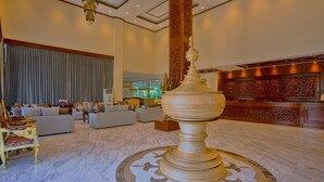 Un hall d’entrée spacieux, agrémenté d’un grand vase décoratif, de fauteuils confortables et d’un espace de réception orné de motifs complexes.