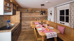 Una cocina con paredes de madera, una mesa de comedor para cuatro personas y un horno empotrado.
