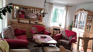 A cozy living room with a wooden cabinet, a dining table, and several upholstered chairs. - Vacation apartment for up to 8 people, 140 sqm, 2 WCs, directly on the L.Heide nature reserve (Bispingen)