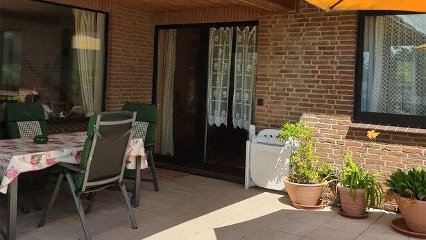 An outdoor patio with a table and chairs, potted plants, and a sliding glass door. - Vacation apartment for up to 8 people, 140 sqm, 2 WCs, directly on the L.Heide nature reserve (Bispingen)