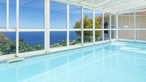 Una piscina interior con grandes ventanales que ofrecen vistas al océano.