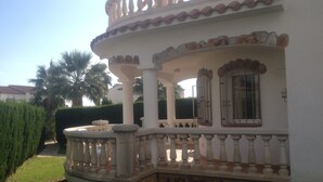 A two-story building with a white exterior, a stone base, and a balcony with balustrades. - Family-friendly bungalow complex with a lot of green and a large pool (Miami Playa)