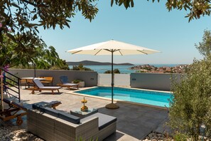 A rooftop pool area with lounge chairs, a table, and an umbrella. - An oasis of tranquility with beautiful ocean views (Sevid)