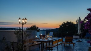 Una terrazza esterna con tavolo e sedie, un lampione e vista sul paesaggio.