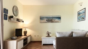 Un soggiorno con divano, televisore e oggetti decorativi su una consolle in legno.
