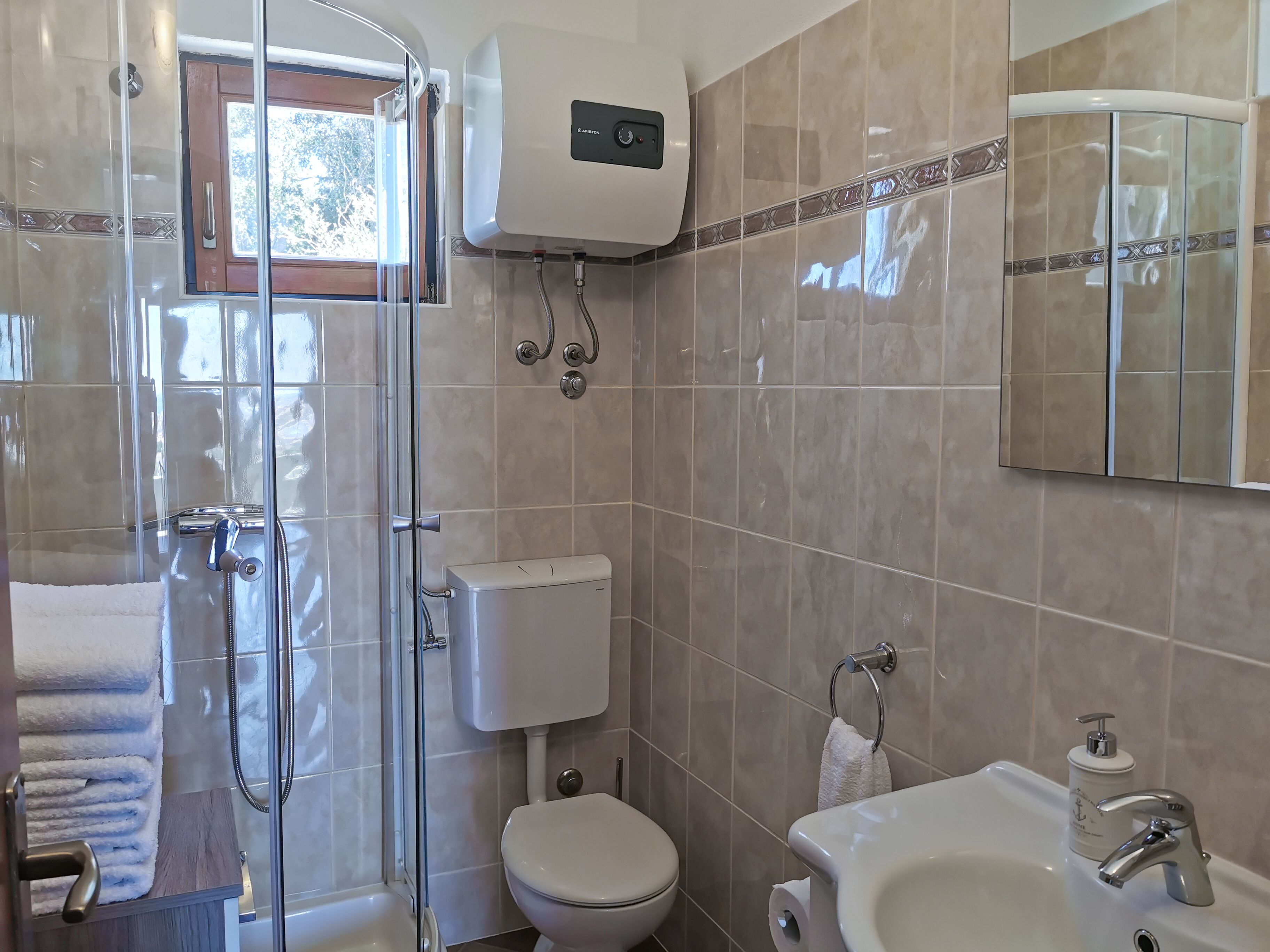 Un bagno con doccia in vetro, un WC e un lavandino con specchio.