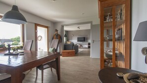 Amplia sala de estar con una mesa de comedor de madera, un sofá y un televisor al fondo.