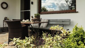 Un patio con mobiliario de mimbre, una mesa de madera y un banco.