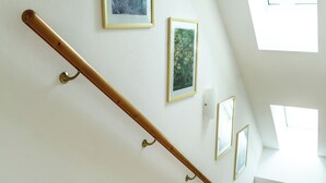 Un escalier avec une rampe en bois, des murs blancs et des tableaux encadrés.