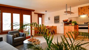 Una sala de estar moderna con un sofá, una mesa de comedor y una cocina con armarios de madera.