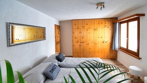 Un dormitorio con cama, un armario de madera, un espejo y una ventana.