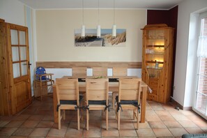 Ein Essbereich mit Holztisch und Stühlen, einem Gemälde über dem Tisch und einem Schrank mit Gläsern.