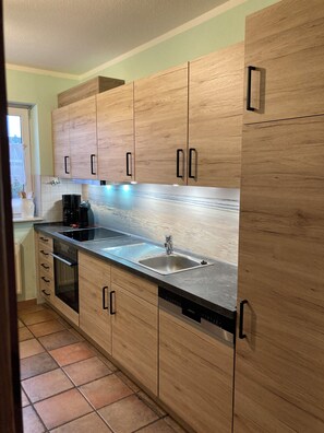 Eine moderne Küche mit Holzschränken, einem Edelstahlspülbecken und einem eingebauten Geschirrspüler.