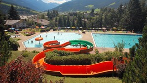 Un complexe hôtelier doté d’une grande piscine, de toboggans aquatiques et offrant une vue sur un paysage montagneux.